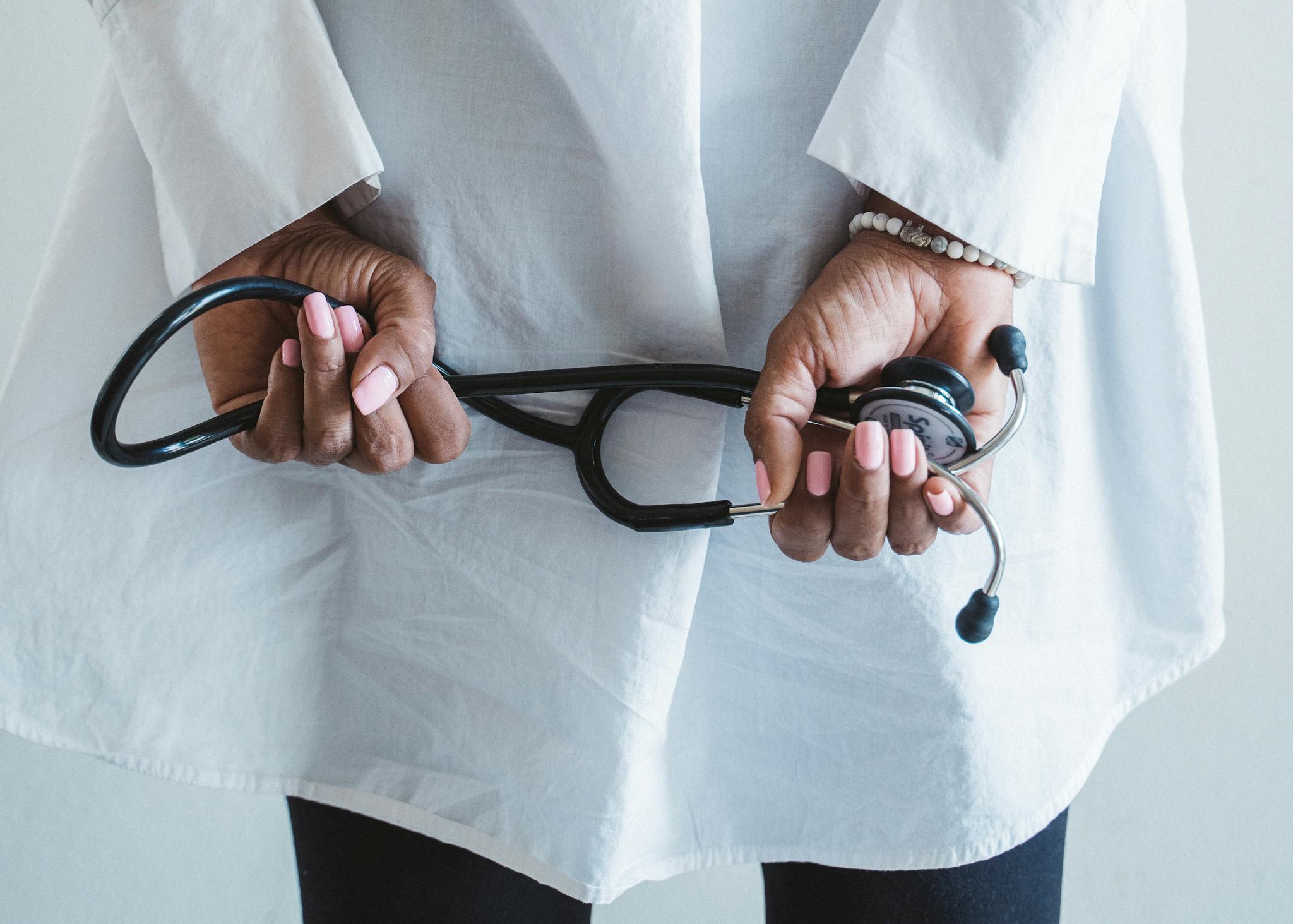 A medical professional holding a stethoscope in a clinical setting.
